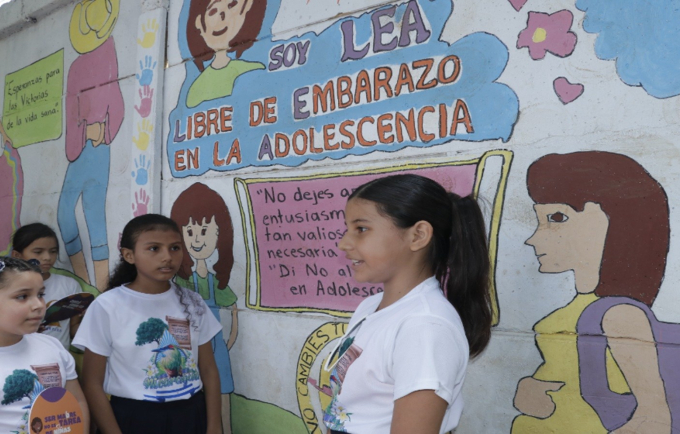 Adolescente de la Escuela Primaria Carrusel en El Viejo, Chinandega muestra el mural en el que destacan el mensaje de LEA que si
